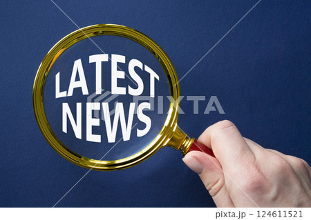 Latest News symbol. Concept word Latest News on magnifying glass. Businessman hand. Beautiful deep blue background. Business and Latest News concept. Copy space 124611521