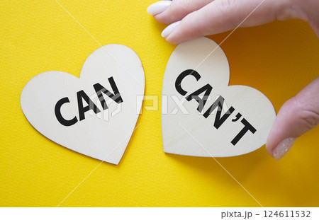 Can or Cant symbol. Concept word Can or Cant on wooden hearts. Businessman hand. Beautiful yellow background. Business and Can or Cant concept. Copy space 124611532