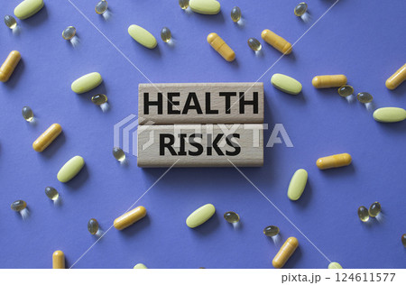 Health Risks symbol. Concept word Health Risks on wooden blocks. Beautiful purple background with pills. Medicine and Health Risks concept. Copy space 124611577