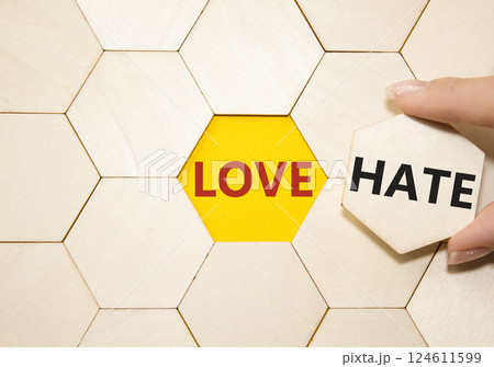 Love vs Hate symbol. Concept word Love vs Hate on wooden puzzle. Businessman hand. Beautiful yellow background. Business and Love vs Hate concept. Copy space Love vs Hate symbol. Concept word Love vs Hate on wooden puzzle. Businessman hand. Beautiful yellow background. Business and Love vs Hate concept. Copy space 124611599