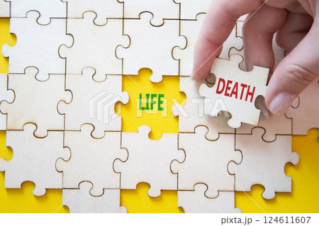 Life or Death symbol. Concept word Life or Death on wooden puzzle. Businessman hand. Beautiful yellow background. Business and Life or Death concept. Copy space Life or Death symbol. Concept word Life or Death on wooden puzzle. Businessman hand. Beautiful yellow background. Business and Life or Death concept. Copy space 124611607