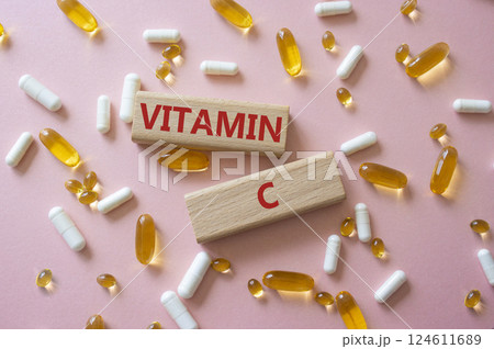 Vitamin C symbol. Concept word Vitamin C on wooden blocks. Beautiful pink background with pills. Medicine and Vitamin C concept. Copy space 124611689