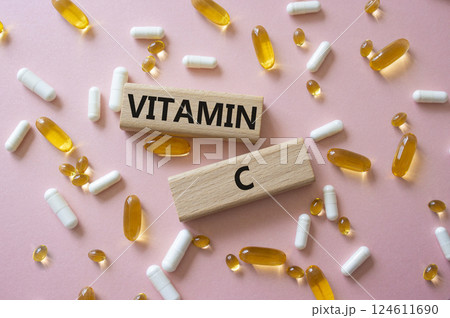 Vitamin C symbol. Concept word Vitamin C on wooden blocks. Beautiful pink background with pills. Medicine and Vitamin C concept. Copy space 124611690