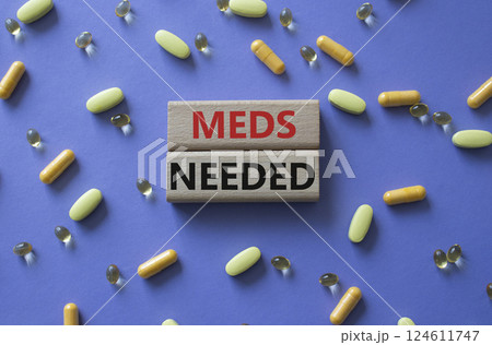 Meds Needed symbol. Concept word Meds Needed on wooden blocks. Beautiful purple background with pills. Medicine and Meds Needed concept. Copy space 124611747