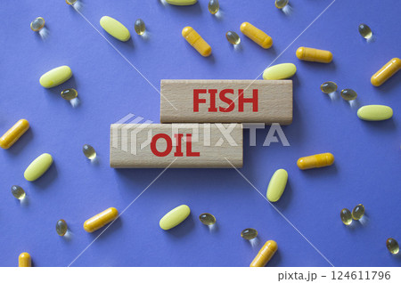 Fish Oil symbol. Concept word Fish Oil on wooden blocks. Beautiful purple background with pills. Medicine and Fish Oil concept. Copy space 124611796