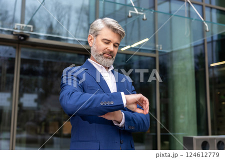 Bearded caucasian businessman looking at his watch while waiting for someone 124612779