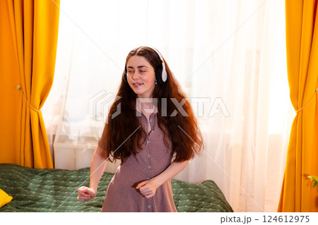 Portrait of happy young woman in braces dancing on the bed and enjoying her playlist Portrait of happy young woman in braces dancing on the bed and enjoying her playlist 124612975