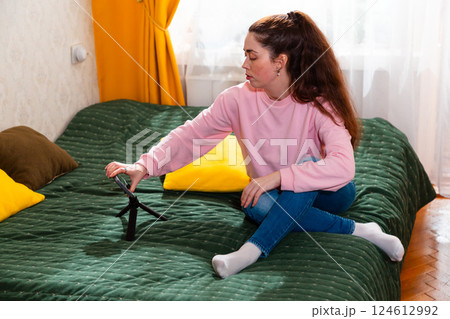 Digital influencer filming an engaging video while sitting on a bed, offering valuable business insights. Mid shot 124612992