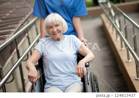 Senior patient in wheelchair receiving health care from unrecognizable professional caregiver 124613437