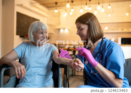 Nurse holding syringe making injection to mature female hospital visitor Nurse holding syringe making injection to mature female hospital visitor 124613463