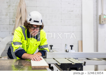 Professional employee male staff worker cutting wooden board on wood workbench in furniture factory Professional employee male staff worker cutting wooden board on wood workbench in furniture factory 124613854