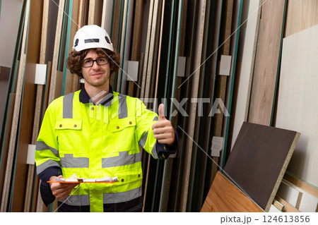 Happy male worker working in wood storage warehouse plywood panel stock inventory in workshop 124613856