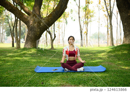 Calm woman practicing meditation outdoors on yoga mat under the trees Calm woman practicing meditation outdoors on yoga mat under the trees 124613866