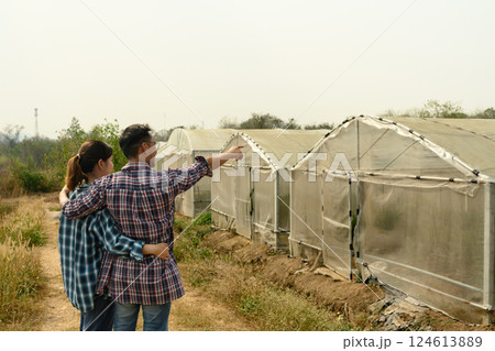 Couple farmers embracing and looking at row of greenhouses, vision, planning and agricultural growth Couple farmers embracing and looking at row of greenhouses, vision, planning and agricultural growth 124613889