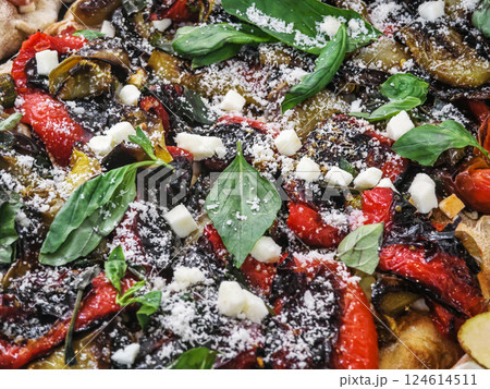 Colorful vegetable pizza topped with herbs and cheese served on a wooden board in a warm setting Colorful vegetable pizza topped with herbs and cheese served on a wooden board in a warm setting 124614511