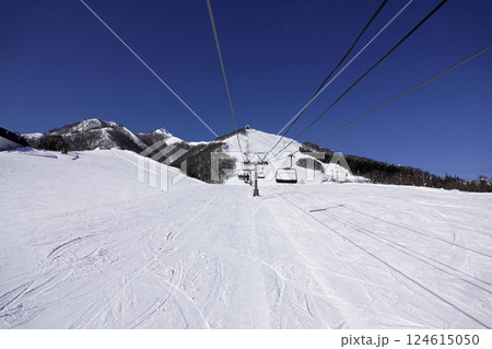 快晴のスキー場 頂上へ続くリフトと広い真っ白なゲレンデ 124615050