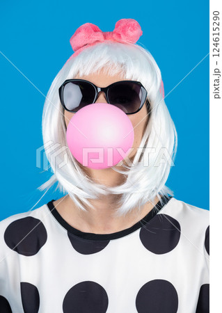 Woman with sunglasses blowing chewing gum bubble studio portrait 124615290