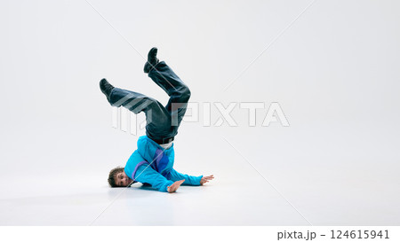 Street dancer balancing upside down with legs extended, defying physics with perfect control against white background with negative space. 124615941