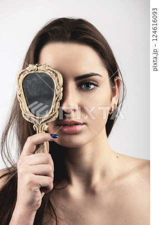 Beautiful woman covers her one eye with old mirror 124616093