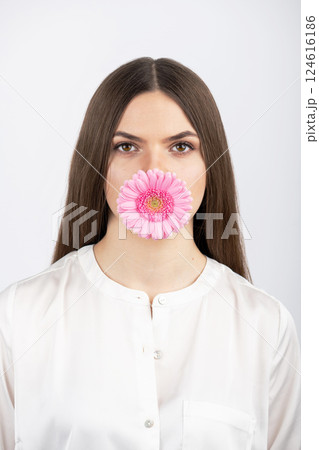 Woman portrait with pink flower blossom in her mouth 124616186