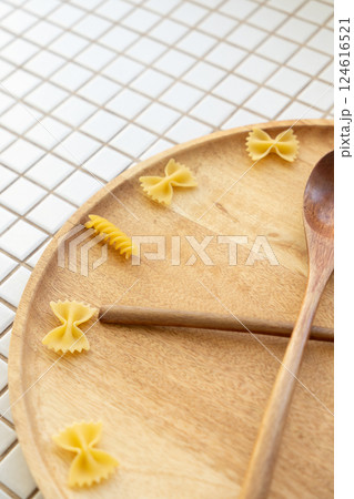 time to eat pasta. wooden plate with fork and spoon in form of clock hands. pasta on plate. time to eat pasta. wooden plate with fork and spoon in form of clock hands. pasta on plate. 124616521