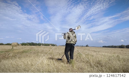 man in a field with a metal detector. treasure hunter searches for valuable metal using a metal detector. Treasure hunt concept. man in a field with a metal detector. treasure hunter searches for valuable metal using a metal detector. Treasure hunt concept. 124617542