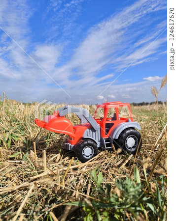 A red tractor is a toy in a harvested cornfield. Agricultural industry. A harvesting company. 124617670