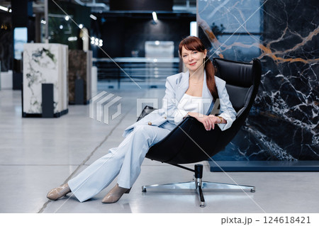 Woman in light blue suit posing in a modern office space Woman in light blue suit posing in a modern office space 124618421