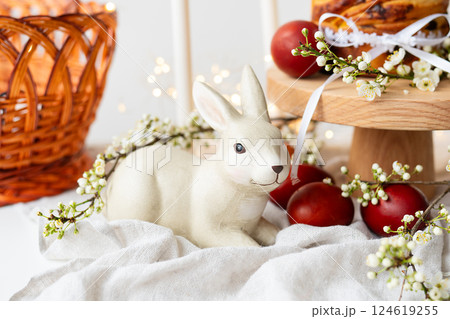 A cozy setting with a ceramic bunny, fresh pastries, and flowers, evoking a warm, homely atmosphere. Easter holiday concept. 124619255