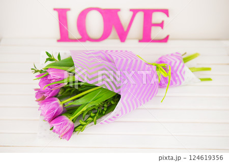 bouquet of purple tulips on white table, wooden letters love 124619356