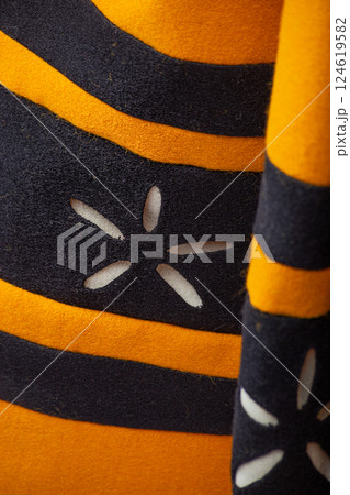 Close-Up Detail of Yellow and Black Medieval Dress. Intricate design featuring contrasting stripes and decorative floral cutouts. Close-Up Detail of Yellow and Black Medieval Dress. Intricate design featuring contrasting stripes and decorative floral cutouts. 124619582