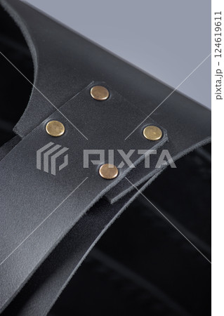 Close-up of Leather Shoulder Straps on Black Cuirass. Detailed view of the black leather armor showing the shoulder straps and brass rivet fastenings. Close-up of Leather Shoulder Straps on Black Cuirass. Detailed view of the black leather armor showing the shoulder straps and brass rivet fastenings. 124619611