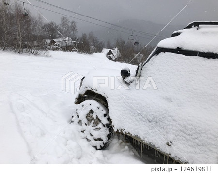 Snow covered off-road vehicle SUV car parked outdoor on a winter ski slope Snow covered off-road vehicle SUV car parked outdoor on a winter ski slope 124619811