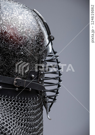 Dark Helmet with Ribbed Faceplate and Chainmail. This image shows a dark, possibly blackened steel, helmet with a pointed top and a distinctive faceplate featuring a series of horizontal ribs. A Dark Helmet with Ribbed Faceplate and Chainmail. This image shows a dark, possibly blackened steel, helmet with a pointed top and a distinctive faceplate featuring a series of horizontal ribs. A 124619862