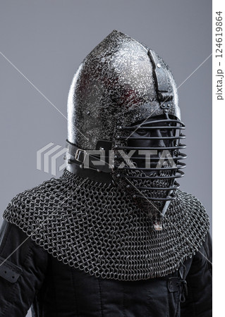 Dark Helmet with Ribbed Faceplate and Chainmail. This image shows a dark, possibly blackened steel, helmet with a pointed top and a distinctive faceplate featuring a series of horizontal ribs. A 124619864