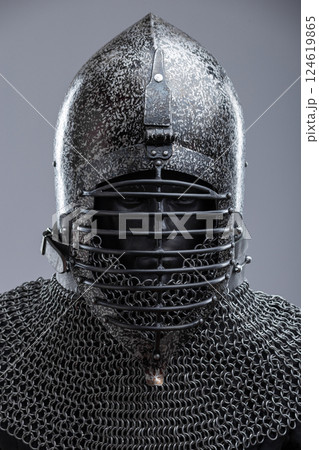 Dark Helmet with Ribbed Faceplate and Chainmail. This image shows a dark, possibly blackened steel, helmet with a pointed top and a distinctive faceplate featuring a series of horizontal ribs. A 124619865