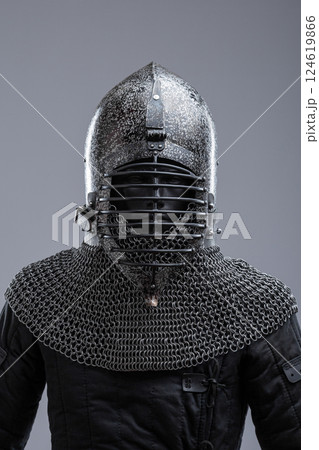 Dark Helmet with Ribbed Faceplate and Chainmail. This image shows a dark, possibly blackened steel, helmet with a pointed top and a distinctive faceplate featuring a series of horizontal ribs. A 124619866