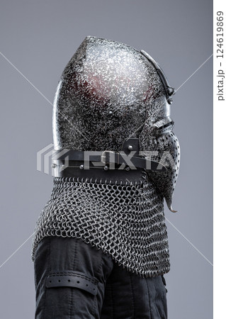 Dark Metal Helmet with Pointed Top and Faceplate. This image shows a dark metal helmet with a pointed top and a faceplate that covers the lower part of the face, featuring several horizontal slits for Dark Metal Helmet with Pointed Top and Faceplate. This image shows a dark metal helmet with a pointed top and a faceplate that covers the lower part of the face, featuring several horizontal slits for 124619869