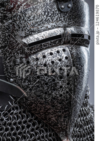 Dark Metal Helmet with Pointed Top and Faceplate. This image shows a dark metal helmet with a pointed top and a faceplate that covers the lower part of the face, featuring several horizontal slits for 124619870