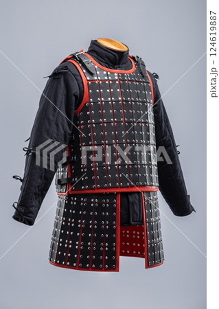 Black Leather Samurai Armor with Red Trim. Traditional Japanese warrior garment featuring layered leather plates and vibrant red accents. Black Leather Samurai Armor with Red Trim. Traditional Japanese warrior garment featuring layered leather plates and vibrant red accents. 124619887