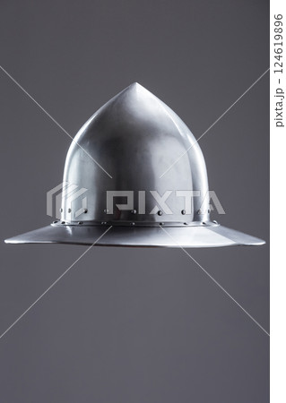 Polished steel medieval infantry kettle hat. Front view of a polished steel medieval kettle hat helmet with pointed dome, wide brim, and rivets on a plain background. Polished steel medieval infantry kettle hat. Front view of a polished steel medieval kettle hat helmet with pointed dome, wide brim, and rivets on a plain background. 124619896