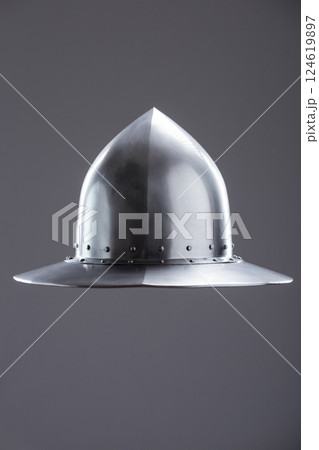 Polished steel medieval infantry kettle hat. Front view of a polished steel medieval kettle hat helmet with pointed dome, wide brim, and rivets on a plain background. Polished steel medieval infantry kettle hat. Front view of a polished steel medieval kettle hat helmet with pointed dome, wide brim, and rivets on a plain background. 124619897