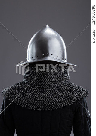 Elegant Medieval Helmet with Gold Accent and Chainmail. Sophisticated head protection featuring a polished finish, golden detail, and attached chainmail. 124619899