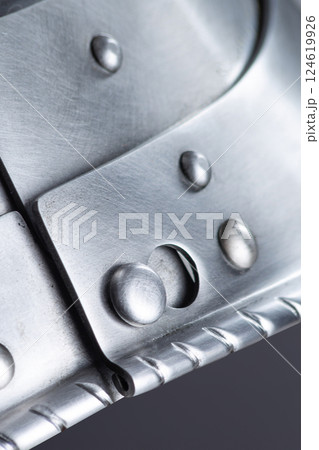 Close-up of a Metal Helmet Fastener with Rivets. This detailed shot shows the construction of a helmet fastener, highlighting the riveted metal plates and hinge mechanism. Close-up of a Metal Helmet Fastener with Rivets. This detailed shot shows the construction of a helmet fastener, highlighting the riveted metal plates and hinge mechanism. 124619926