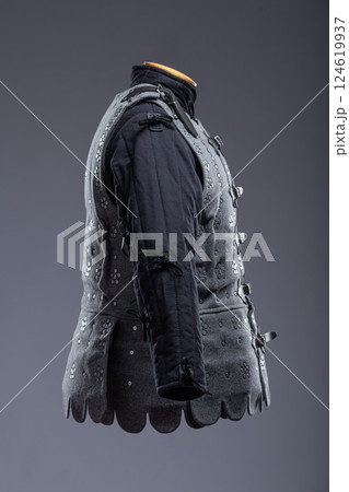 Gray Medieval Brigandine Armor with Leather Straps. This gray brigandine features overlapping metal plates riveted to a fabric base, secured with leather straps. 124619937