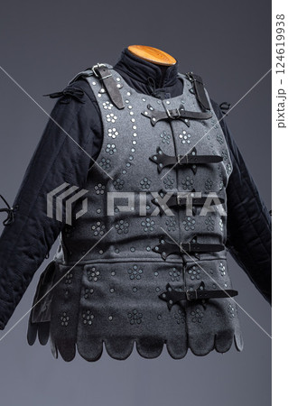 Gray Medieval Brigandine Armor with Leather Straps. This gray brigandine features overlapping metal plates riveted to a fabric base, secured with leather straps. 124619938