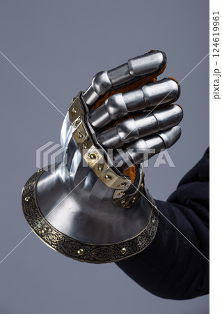 Silver Hourglass Gauntlets with Brass Details. This image shows a close-up of a pair of shiny silver hourglass gauntlets, featuring articulated fingers and brass accents along the edges and rivets. Silver Hourglass Gauntlets with Brass Details. This image shows a close-up of a pair of shiny silver hourglass gauntlets, featuring articulated fingers and brass accents along the edges and rivets. 124619961