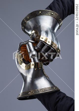 Pair of Silver Medieval Gauntlets with Decorative Brass Trim. This image shows a pair of shiny silver medieval gauntlets, featuring articulated fingers, decorative brass trim along the cuffs, and Pair of Silver Medieval Gauntlets with Decorative Brass Trim. This image shows a pair of shiny silver medieval gauntlets, featuring articulated fingers, decorative brass trim along the cuffs, and 124619962