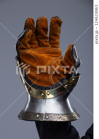 Silver Hourglass Gauntlets with Brass Details. This image shows a close-up of a pair of shiny silver hourglass gauntlets, featuring articulated fingers and brass accents along the edges and rivets. Silver Hourglass Gauntlets with Brass Details. This image shows a close-up of a pair of shiny silver hourglass gauntlets, featuring articulated fingers and brass accents along the edges and rivets. 124619963
