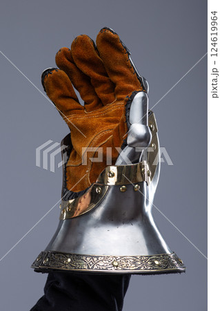 Silver Hourglass Gauntlets with Brass Details. This image shows a close-up of a pair of shiny silver hourglass gauntlets, featuring articulated fingers and brass accents along the edges and rivets. 124619964
